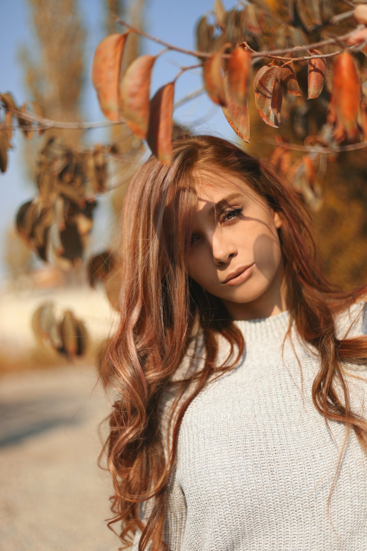 Woman in a soft knit sweater among autumn leaves – Fall Winter 26 at ANIMI Malcesine